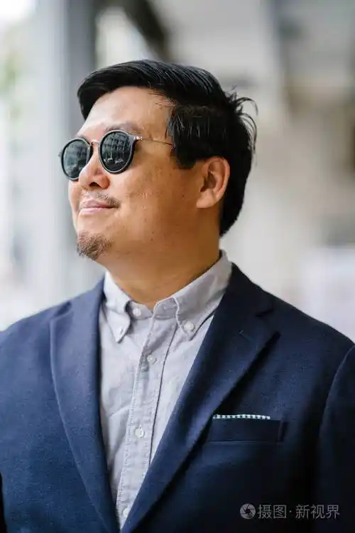 一位中年中国亚裔男子(新加坡人)的肖像,穿着智能休闲,站在城市里.