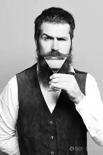 英俊的大胡子的男人,留着长胡子,胡子时尚头发脸上有严重品尝杯含酒精