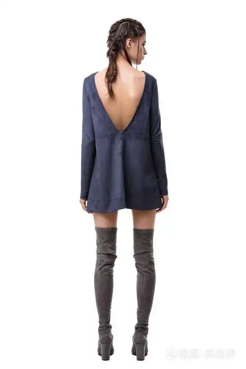 年轻的女士从后面站着穿着深蓝色的绒面连衣裙背部有剪裁膝盖有白色