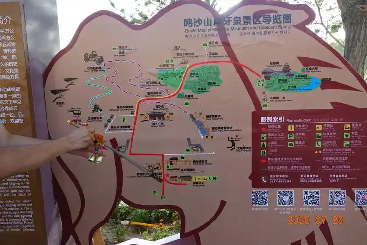 鸣沙山月牙泉景区导游图前,导游小祁手持他独特的导游杆,给大家讲解.