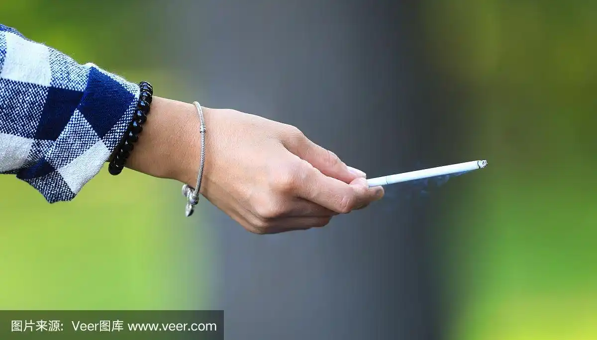 手拿一根香烟的女孩特写,不健康的生活方式观念