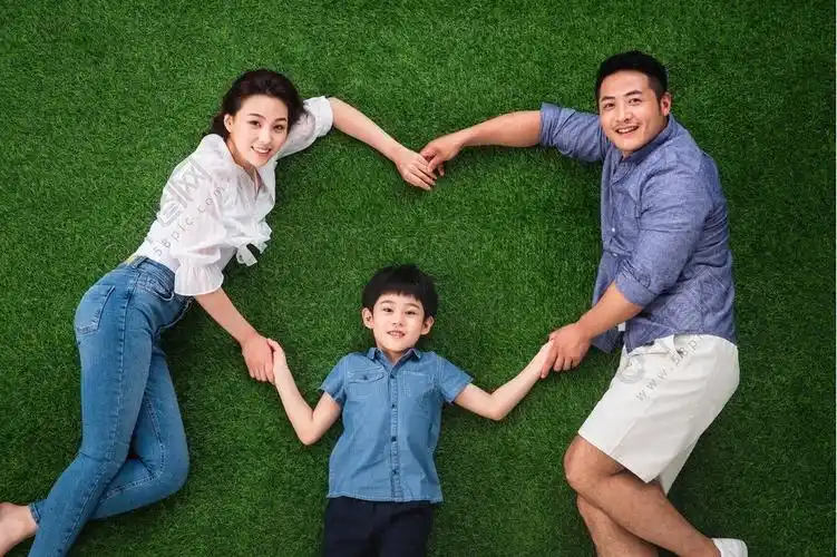 幸福的一家三口在草地上摆成心形