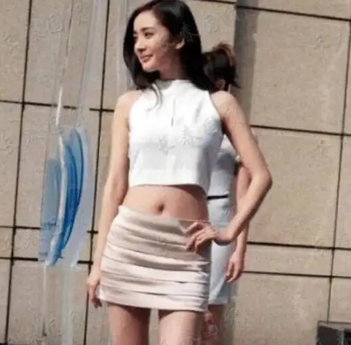 从照片中可以看出,那个时候的杨幂身穿一件白色的露肚脐短装,搭配了一