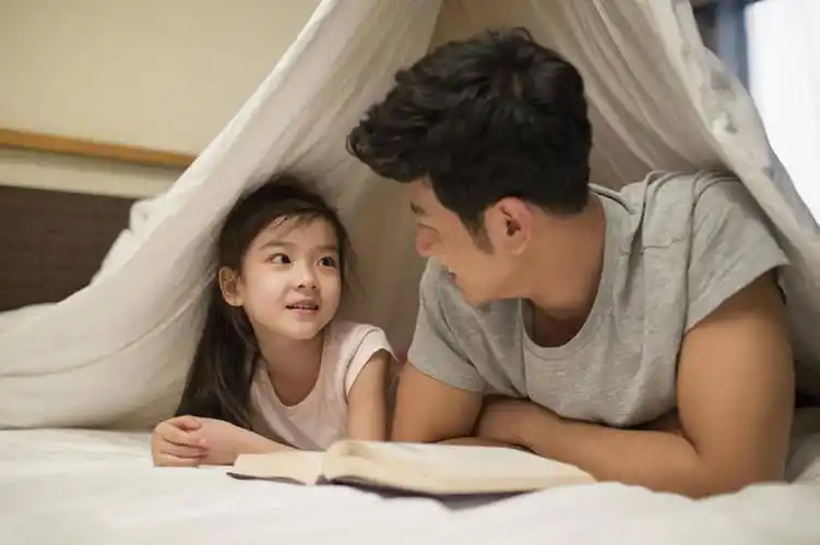小女孩和爸爸在床上看书