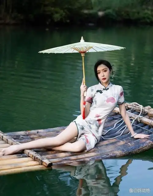 在江南水乡,一位穿着旗袍的美女坐在竹筏上,随着水流轻轻飘动.