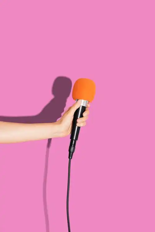 手拿着粉红色墙壁的麦克风