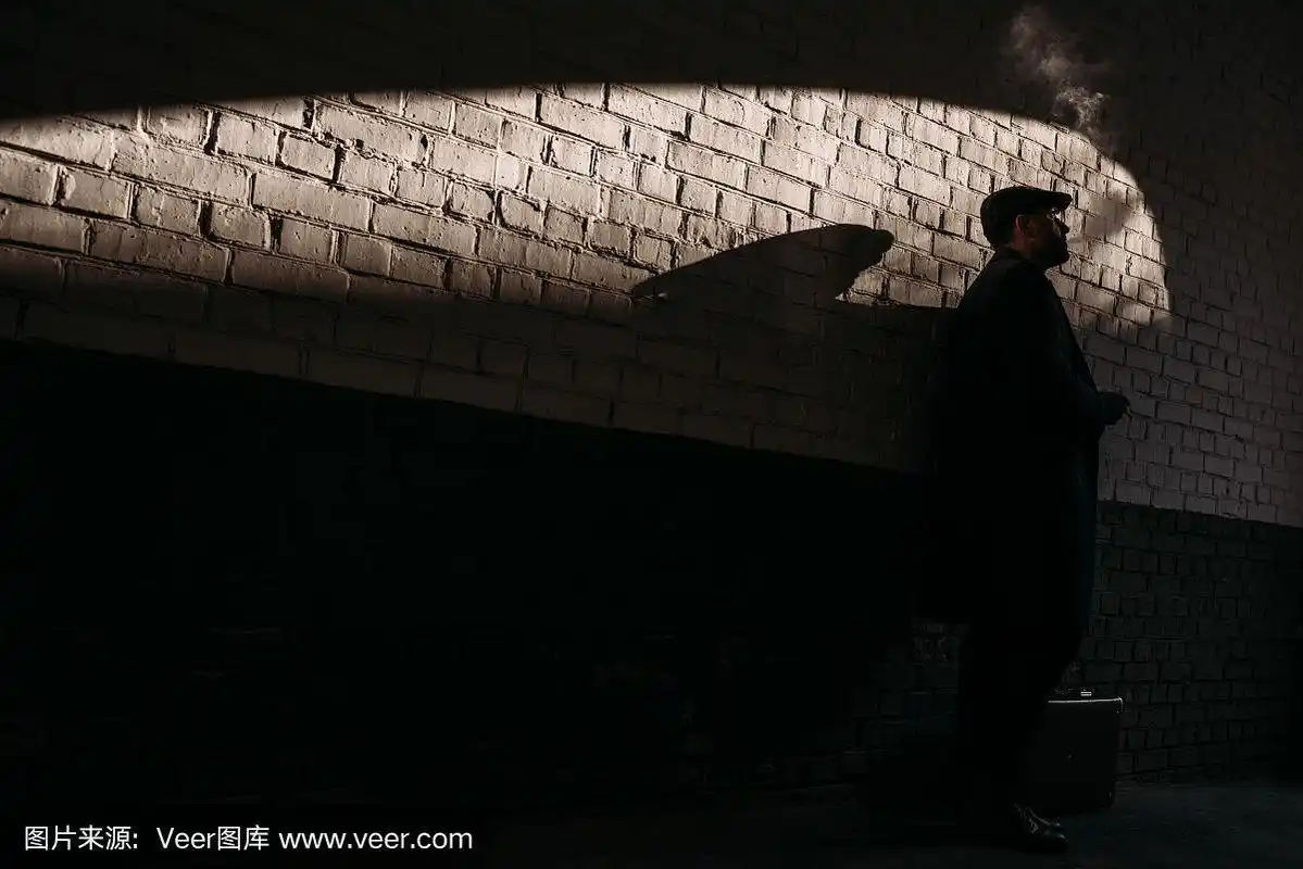 砖墙前吸烟男子的剪影
