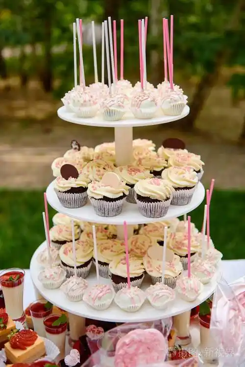 糖果棒上有草莓蛋糕片,奶油甜点在玻璃杯里,纸杯蛋糕和蛋糕放在户外的