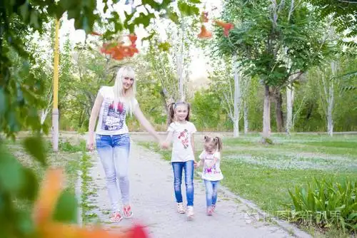 年轻的母亲和两个女儿在草丛中玩