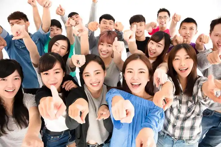 快乐年轻组手指向相机的合拍青春活力