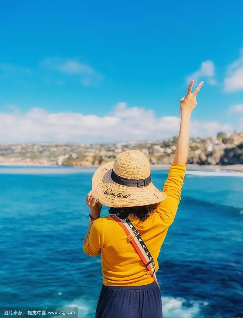 一位年轻女性在美国加州海边度假举手的背影