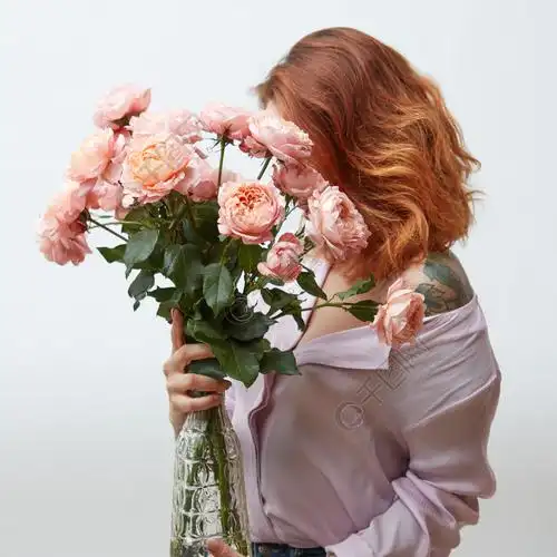 有拿着大花束桃红色玫瑰在一个玻璃花瓶的纹身花刺的一名妇女在与拷贝