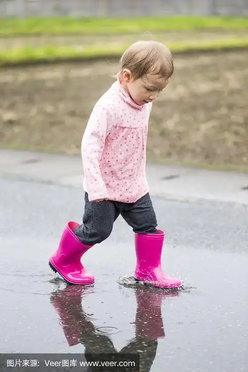 穿着雨靴的小女孩走过水坑