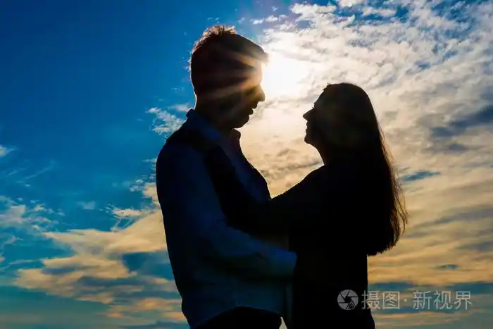 爱拥抱在日落时夫妻的剪影