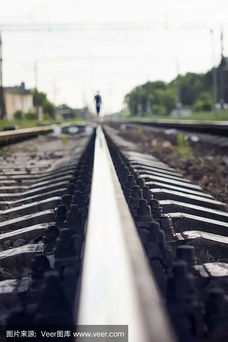 一个人在火车轨道上行走的剪影