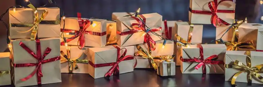 一堆礼物包裹在工艺纸上,上面有红色和金色的丝带,放在黑色的木桌上