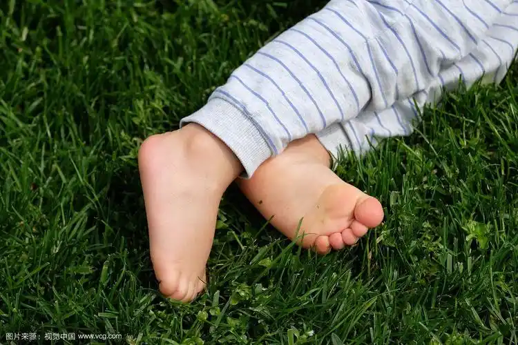 婴儿赤裸的脚在绿色的草地背景孤立在绿色的背景上的特写.