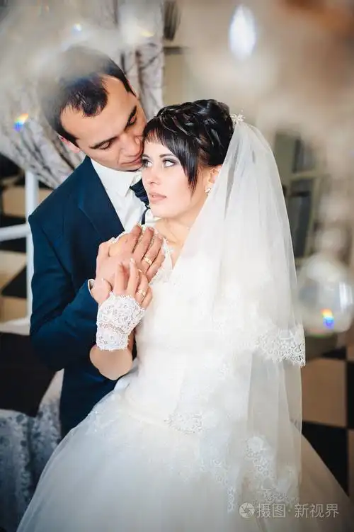 迷人的新娘新郎用拥抱和亲吻他们的婚礼庆典在豪华的