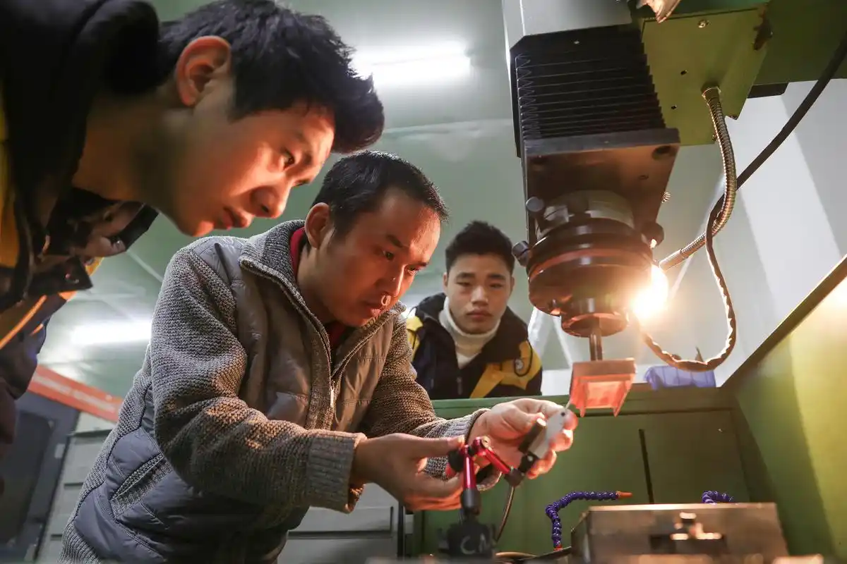 四川省华蓥市职业教育中心的学生认真听取专业老师(中)讲授操作技能