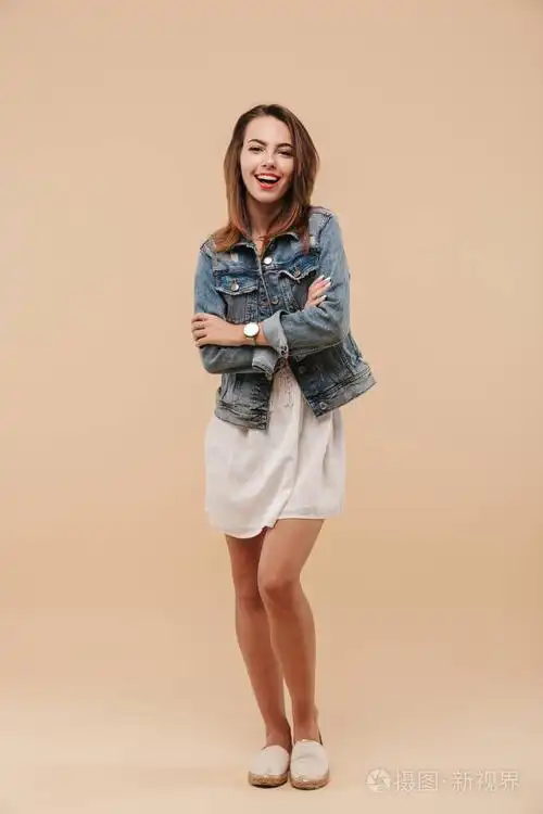 一个穿着夏装,双臂交叉,米色背景的微笑少女的全身画像照片-正版商用