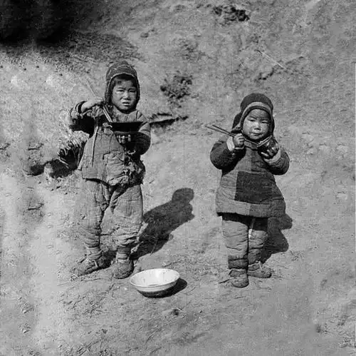 1917年的河南开封,两小孩穿着破旧的棉衣,不知道吃的啥?