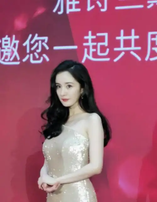 杨幂身着一袭香槟金斜肩礼服亮相活动现场,红唇大波浪明艳动人