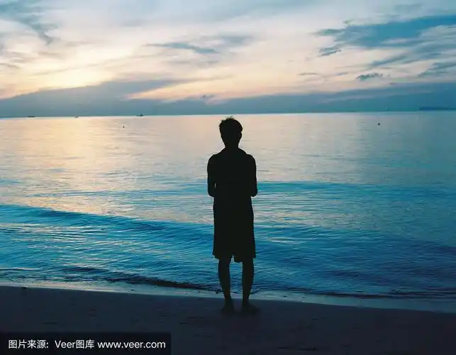 一个男人的剪影独自站在海滩上