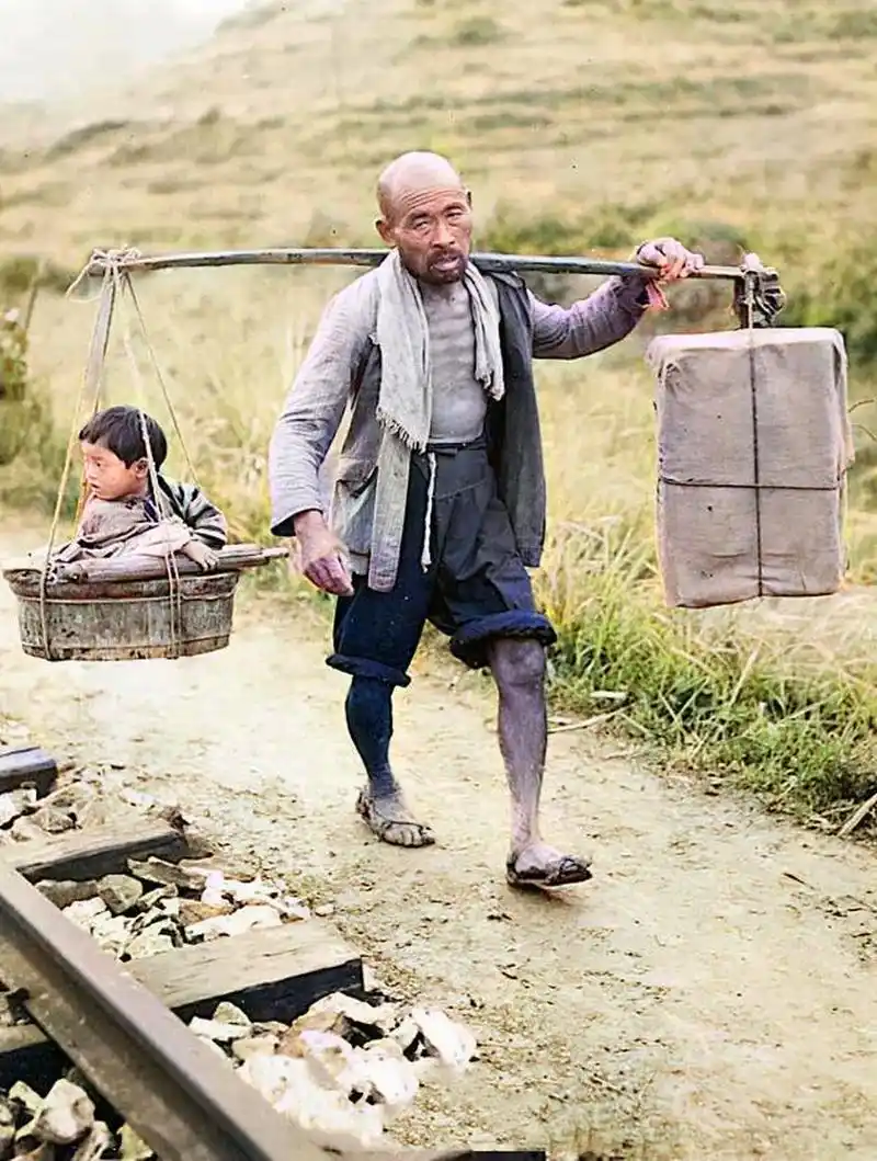 1922年,一位骨瘦如柴的父亲挑着一个沉重的担子,一头是货物,一头是则