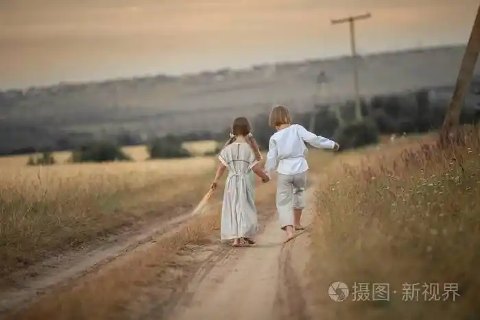 两个穿着衬衫和衣服的孩子在乡间小路上奔跑