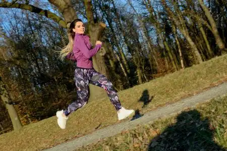 金发女性,五颜六色的紧身裤和紫色的上衣.活跃的跑步者与释放的头发.