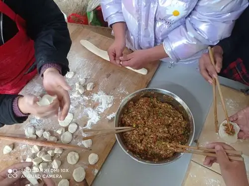 王校长和学生们一起擀饺子皮,包饺子,大家有说有笑.