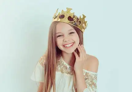 迷你小姐年轻快乐的女孩度假戴一顶王冠和一件白色的