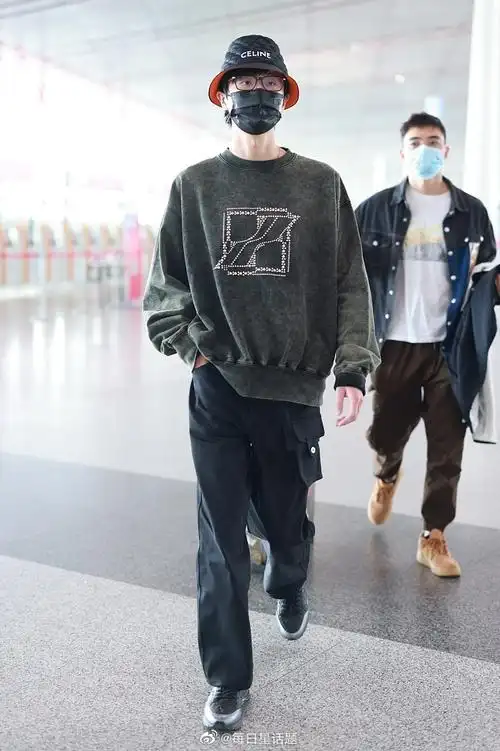 2022年4月9日,北京,许嵩穿墨绿色卫衣戴celine渔夫帽现身机场,帅气