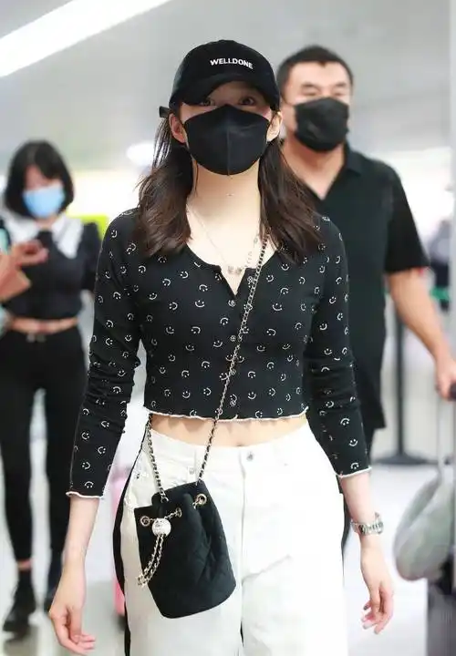 机场街拍时,关晓彤又换了一套黑白色系的穿搭造型,黑色露脐长袖搭配