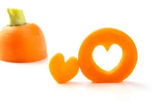 白色背景上切出心形的胡萝卜片