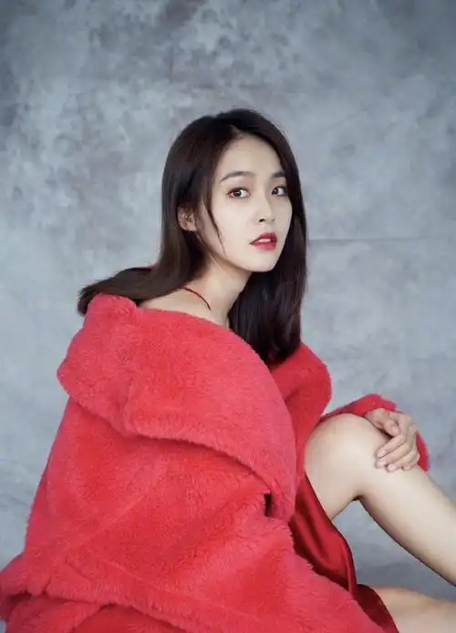 张佳宁在西瓜红的羊羔毛大衣里面搭配了一件正红色的丝绸吊带裙.