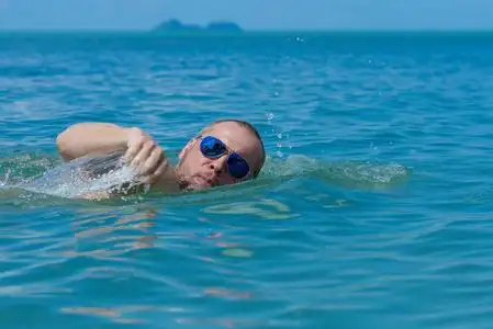 戴墨镜的男运动员在海里的水里游泳照片