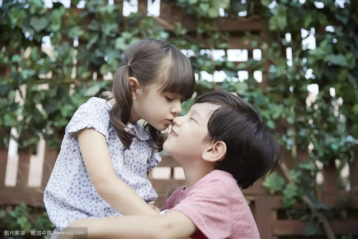 幼儿园男孩抬头看着女孩接吻的照片