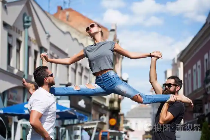 美丽的健身运动女人做劈腿英俊的男人户外