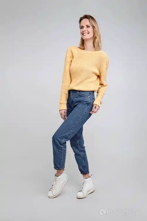 一个穿着时髦衣服的金发美女的全身肖像在白色背景前摆姿势