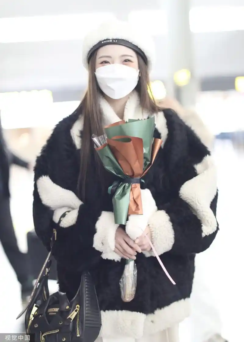 组图:郑乃馨戴白色贝雷帽现身机场 手捧粉丝赠送花束笑眼弯弯