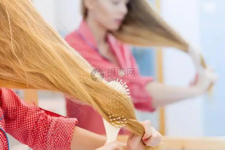 女孩在浴室梳她的长头发用刷子照镜女孩在照顾下刷新发型理概念女人在