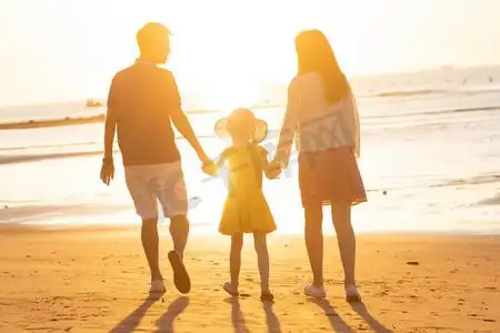 夕阳下一家三口在海边玩耍