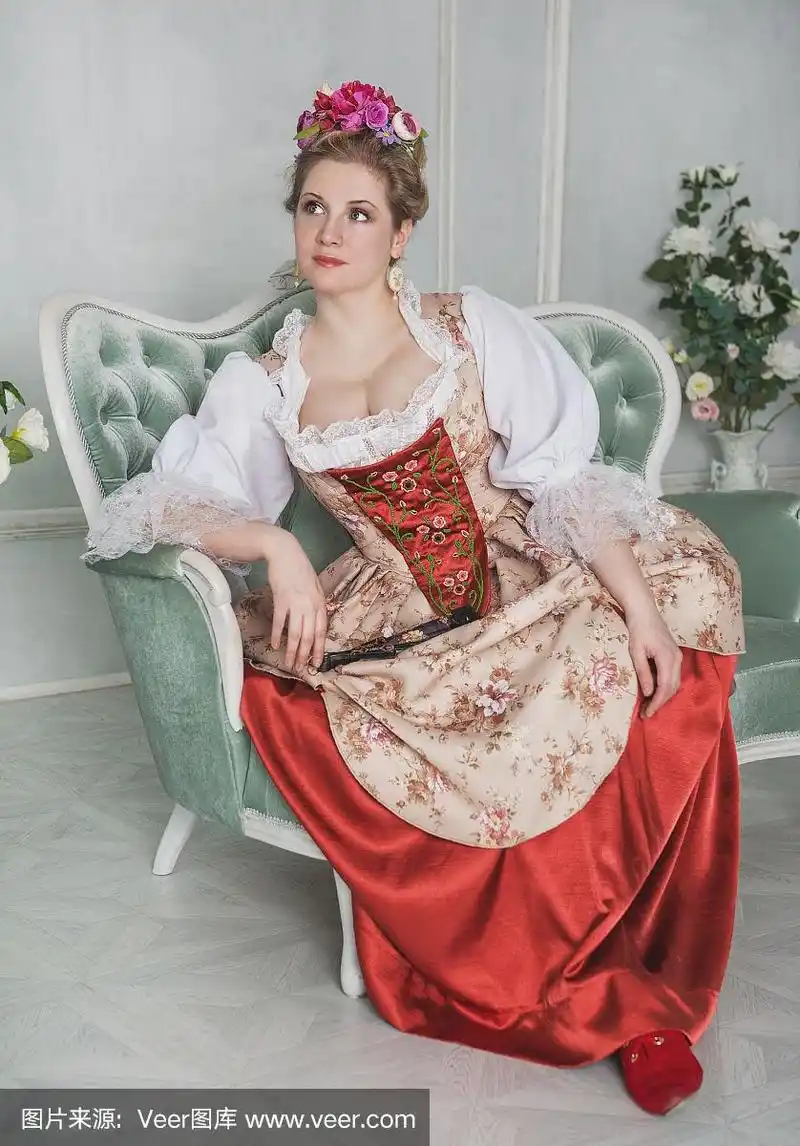 漂亮的女人穿着老式的中世纪服装坐在沙发上
