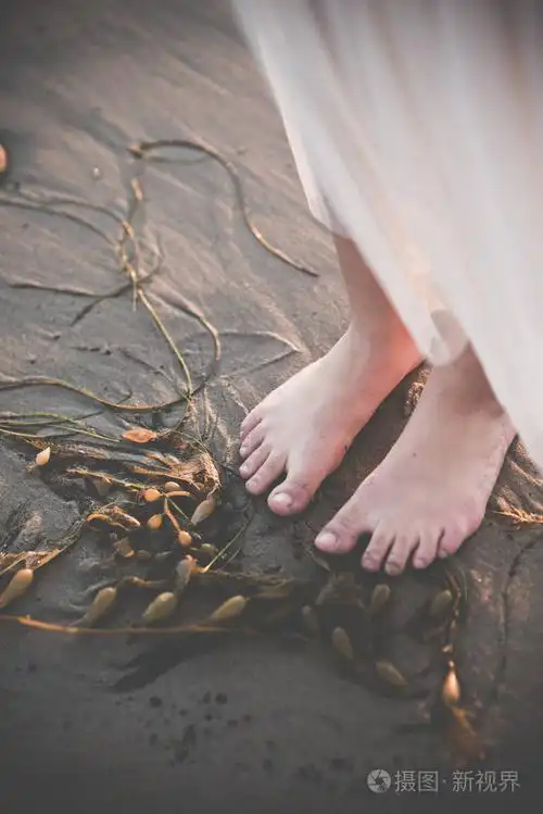 下午在沙滩上赤脚站着的女性