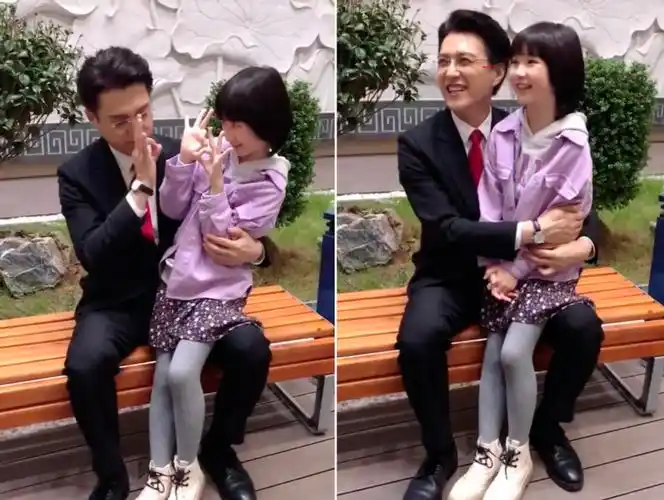 靳东和剧中女儿兴奋玩闹,环抱小女孩不撒手,咧嘴大笑出眼部褶子