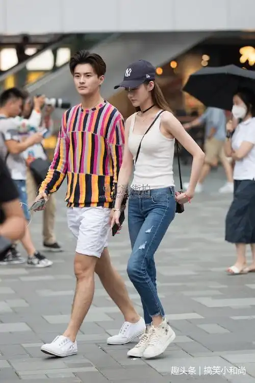 路人街拍小姐姐牛仔短裤搭配红色针织短衫一双小白鞋步履轻盈