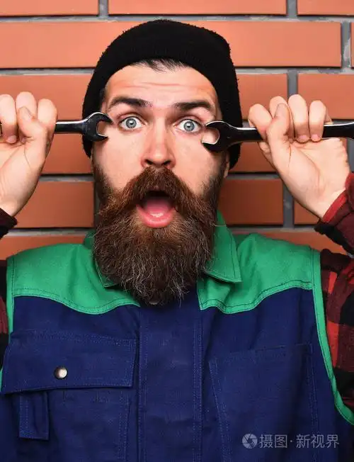 大胡子野蛮白种人机修工持有金属扳手