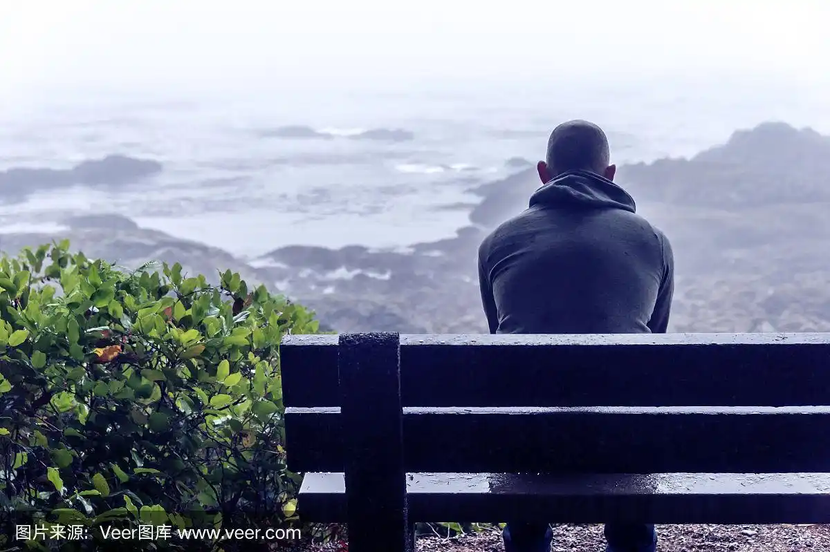 一个悲伤而孤独的人坐在长凳上俯瞰温哥华岛上的大海