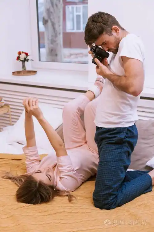 一对夫妇在卧室里拍照年轻人在舒适的床上为女友拍照留念